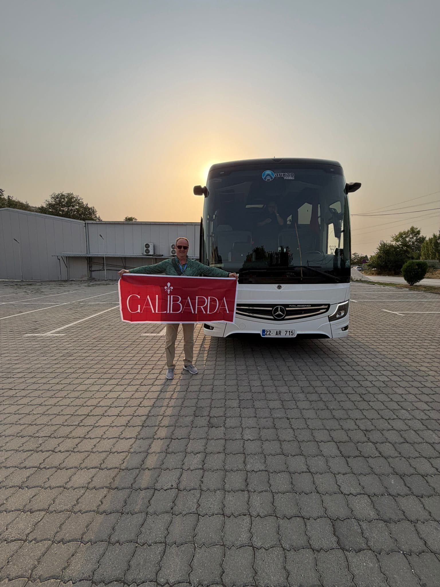 Galibarda guide holding the Galibarda flag in front of a coach at sunrise